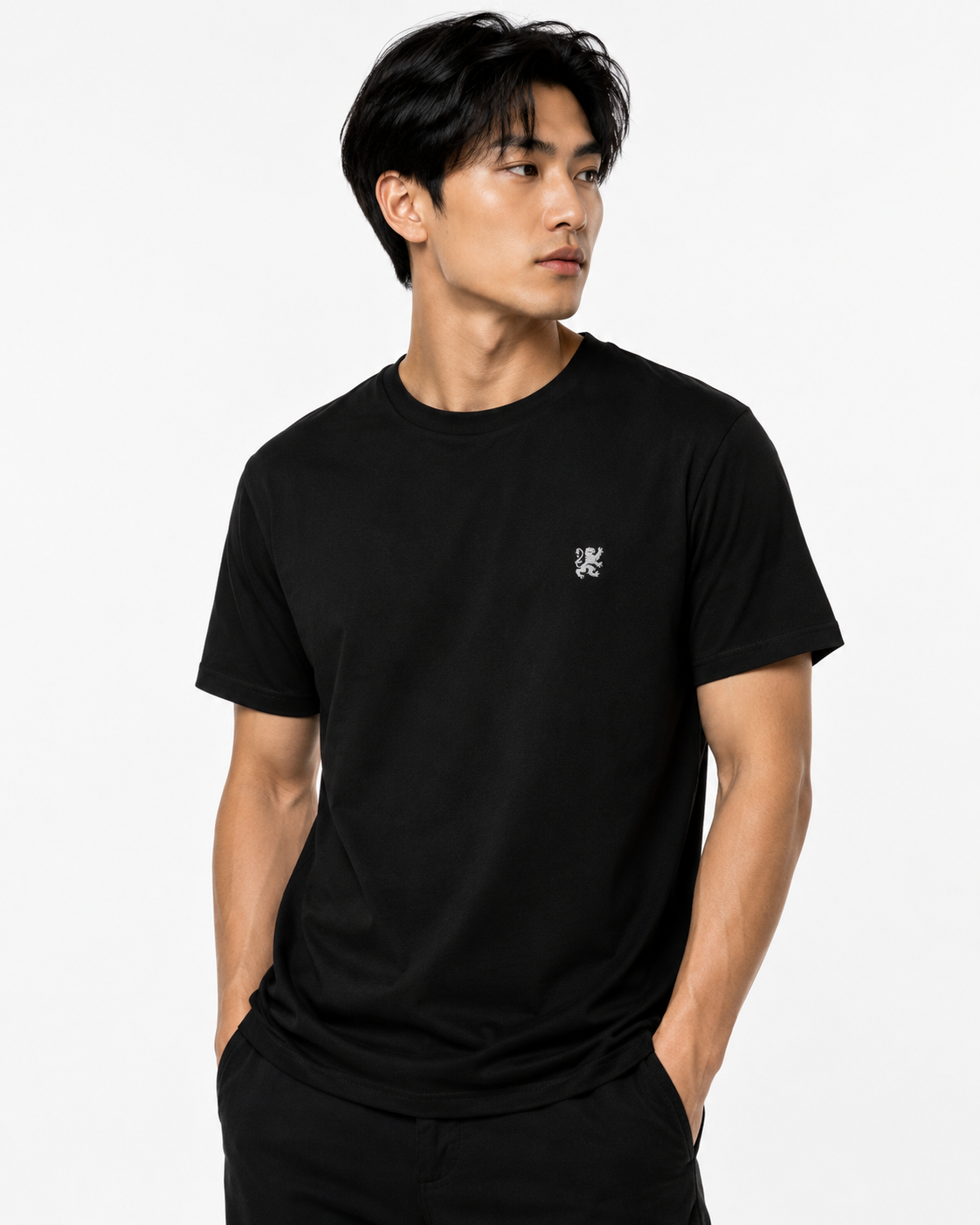 Asian male model wearing a black Agilis Cultus t-shirt with small lion chest embroidery on a clean white studio background.