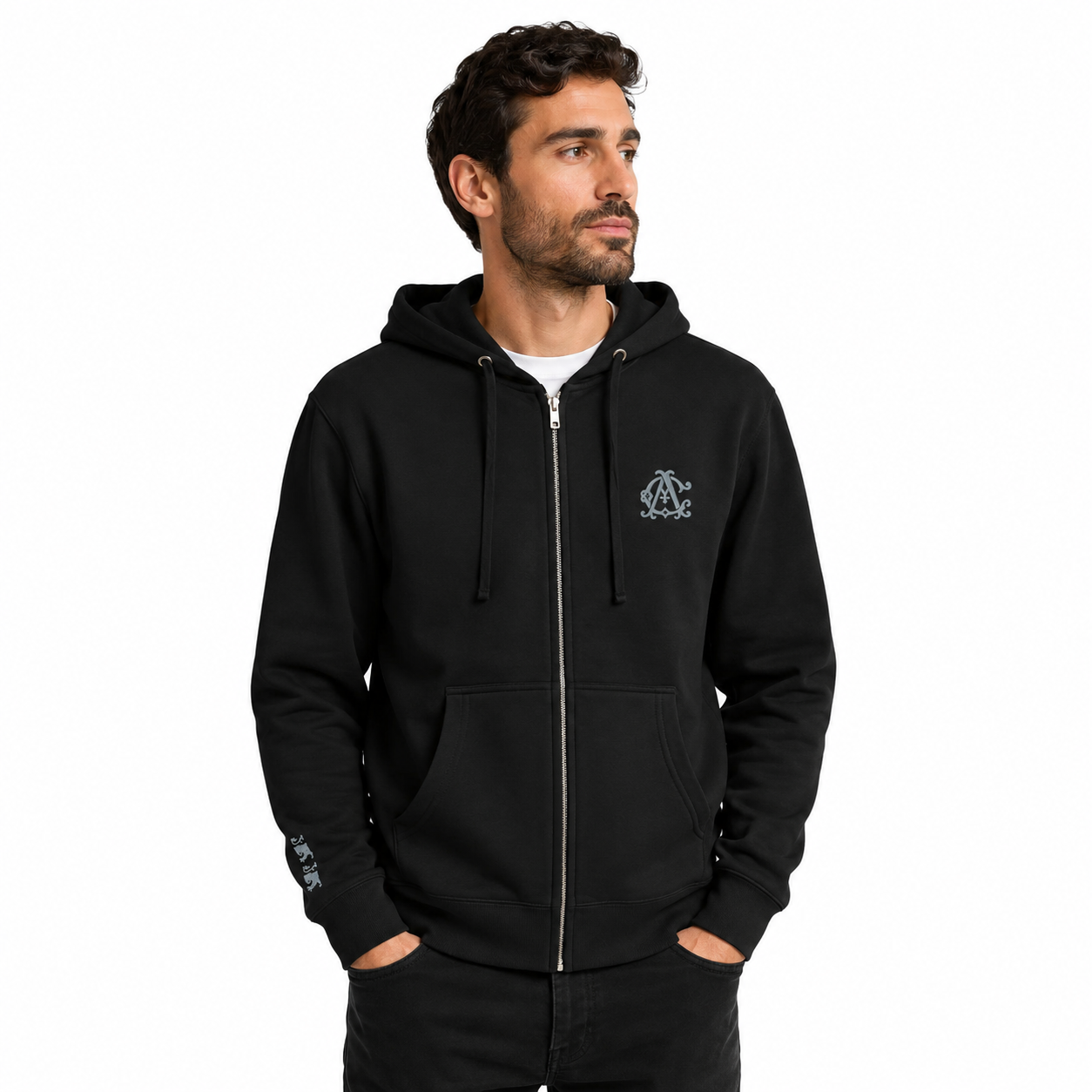 Male model wearing a black Agilis Cultus zip hoodie with chest monogram embroidery and partially visible sleeve lion embroidery on a clean white studio background.