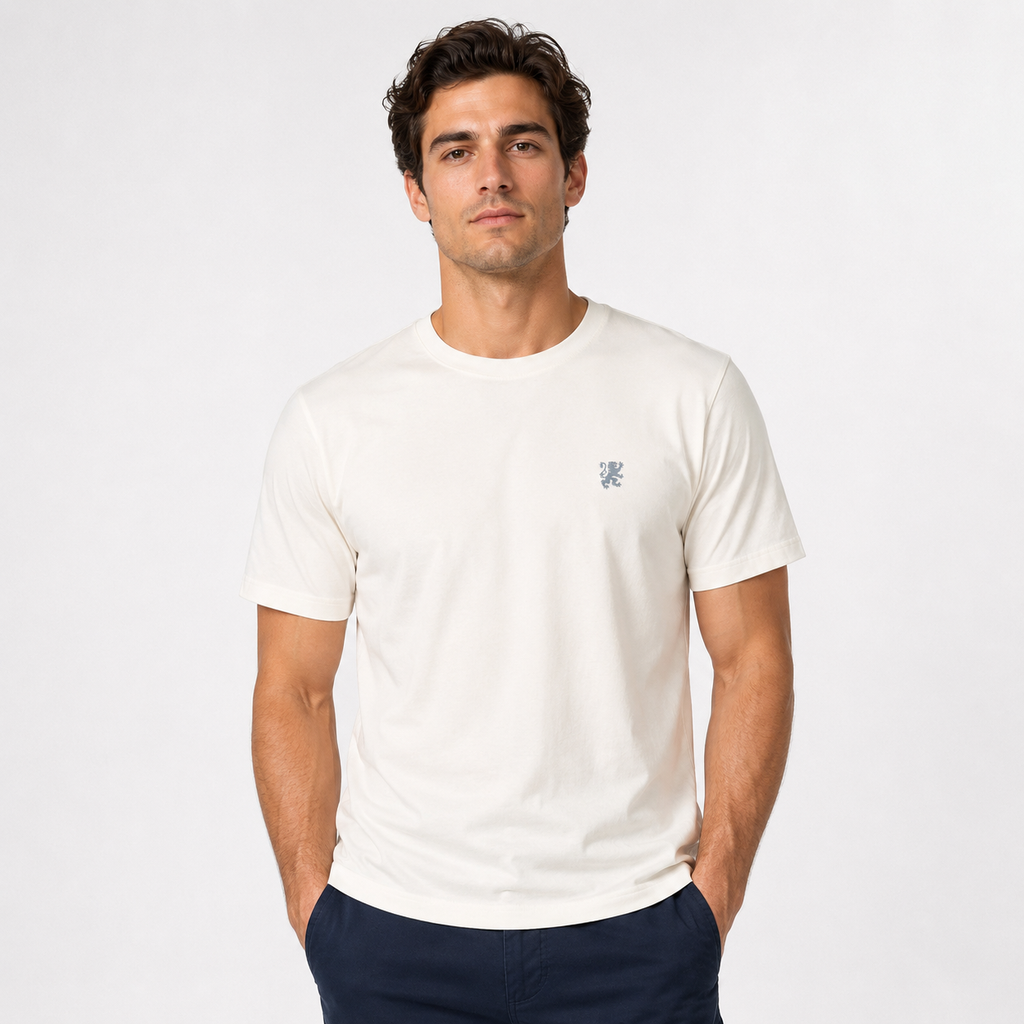 Ivory Agilis Cultus t-shirt with small embroidered lion logo on the chest and printed neck label on a white background.