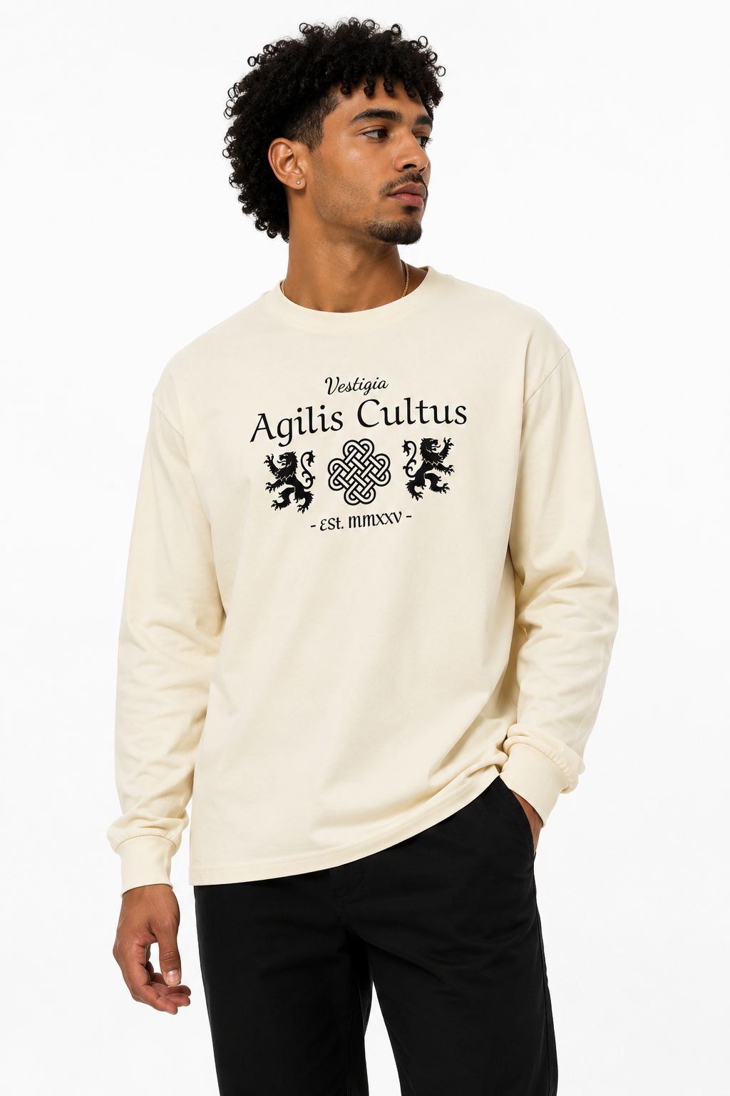 Male model wearing an ivory Agilis Cultus Vestigia long sleeve shirt with black lion and Celtic knot artwork on a clean white studio background.
