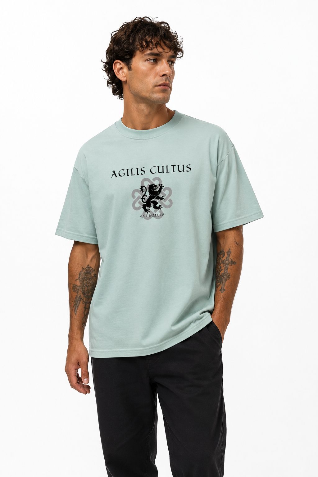 Male model wearing a light mint Agilis Cultus graphic t-shirt with black front logo and heraldic lion artwork on a clean white studio background.