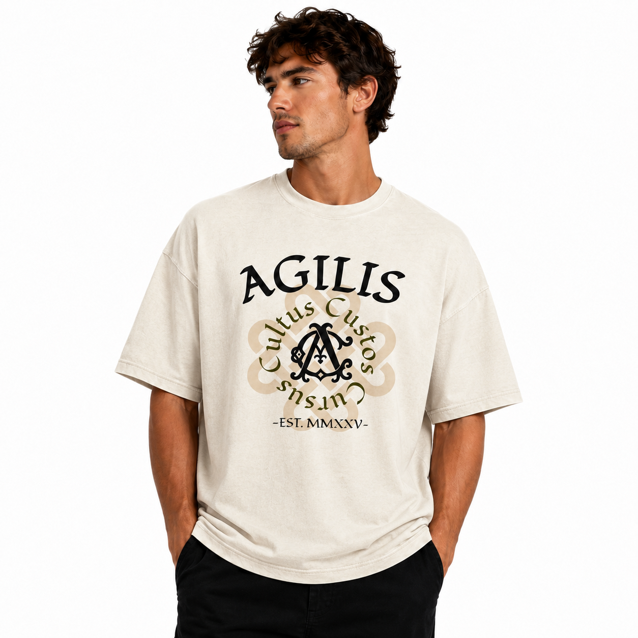 Male model wearing an oversized garment-dyed Agilis Cultus graphic t-shirt with bold front artwork on a clean white studio background.