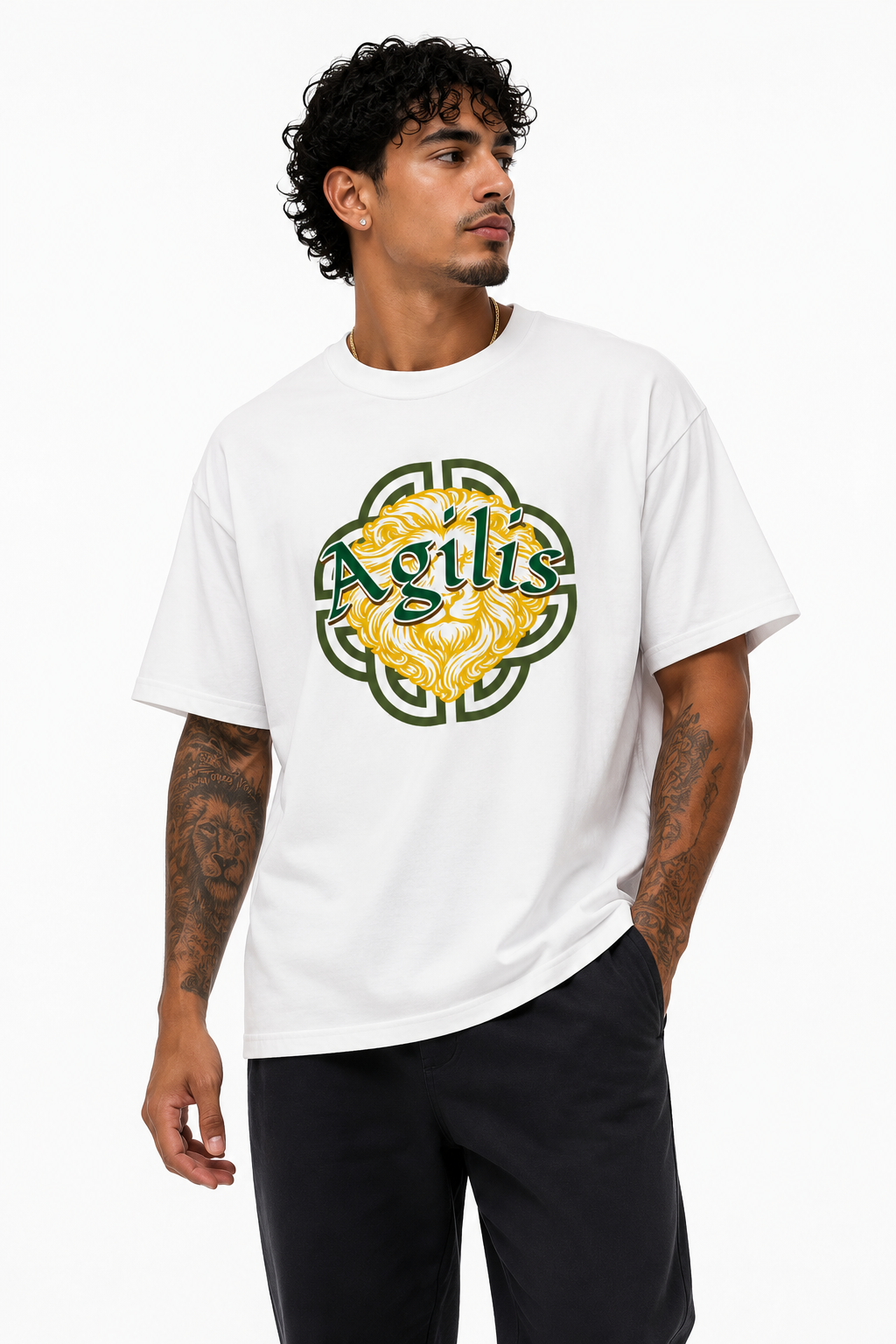 Male model wearing a white Agilis graphic t-shirt with green and gold lion artwork, black pants, and a clean white studio background.